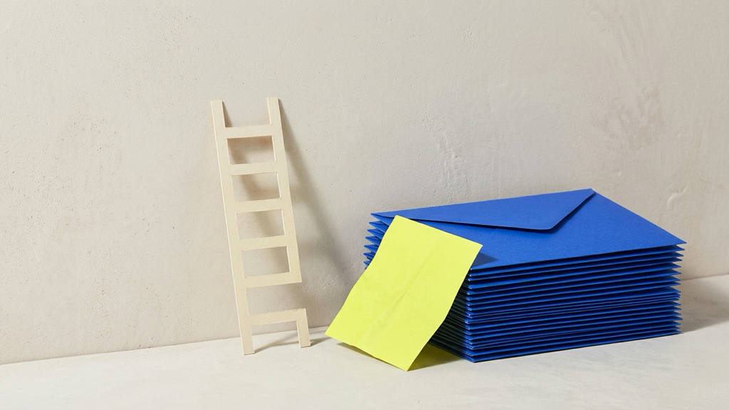 A stack of cobalt blue payroll envelopes on a pale wall beside a small paper ladder missing its lowest rung, with one acid-yellow pay slip set apart.